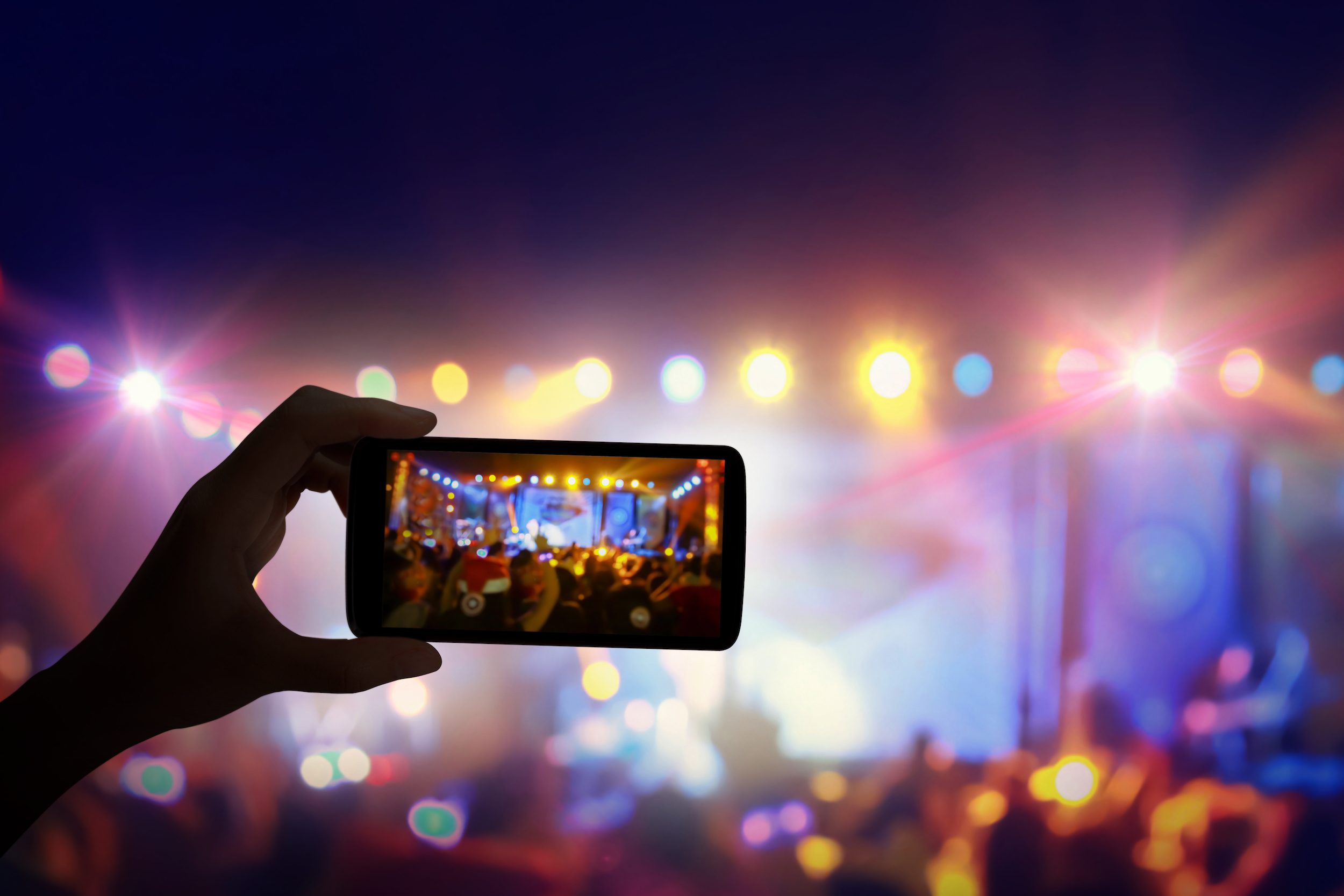 hand holding camera phone filming video of crowd